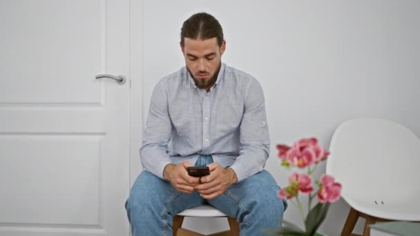 Ung Latinamerikan Man Med Smartphone Sitter Stolen Ser Upprörd Väntrummet — Stockvideo