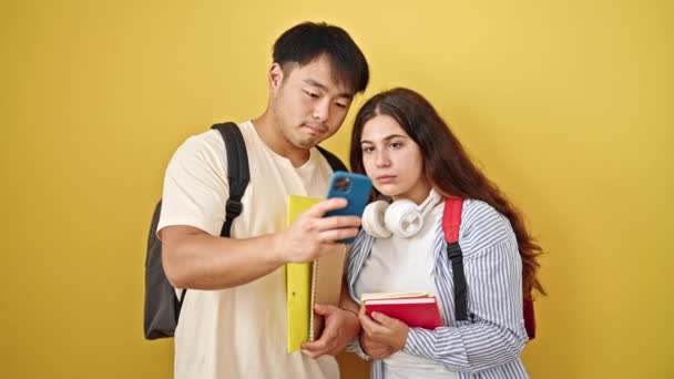 Studentinnen Und Studenten Halten Bücher Mit Smartphone Über Isoliertem Gelben — Stockvideo