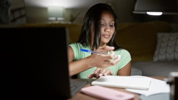 自宅でノートを取るノートパソコンを使用している若いラテン系女性 — ストック動画