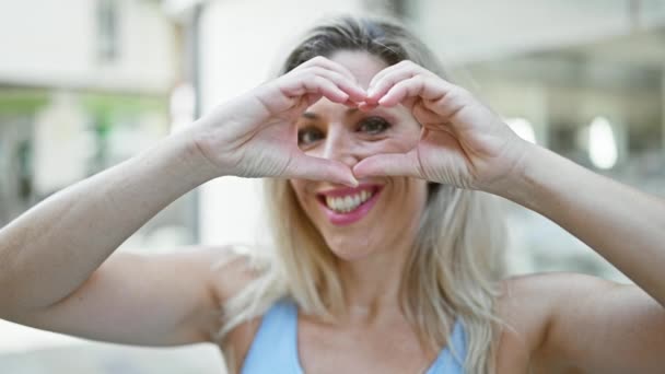 Jonge Blonde Vrouw Glimlachen Zelfverzekerd Doen Hart Gebaar Met Handen — Stockvideo