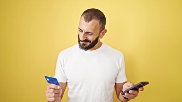 用智能手机和信用卡在孤立的黄色背景下购物的年轻人 — 图库视频影像