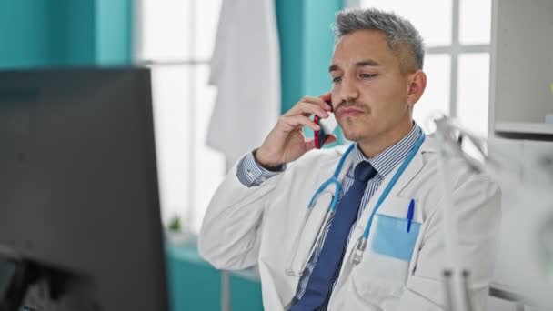 Mladý Hispánský Muž Lékař Pomocí Počítače Mluví Smartphone Klinice — Stock video