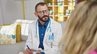 Genç İspanyol doktor, klinikteki hastayla tıbbi rapor yazıyor.