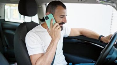 Genç İspanyol adam akıllı telefondan konuşuyor. Arabada oturuyor ve sokakta tartışıyor.