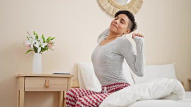 Genç, güzel İspanyol bir kadın uyandığında akıllı telefon kullanıyor yatak odasında esniyor.