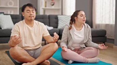 Erkek ve kadın çift evde yoga egzersizi yapıyor.