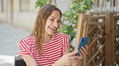 Kahvecinin terasında kendine güvenen genç sarışın kadın.