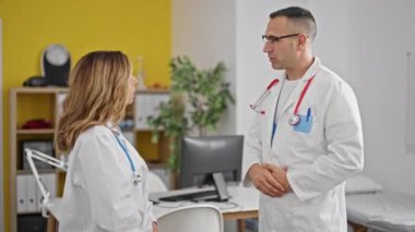 Kadın ve erkek doktorlar konuşuyor ve klinikte el sıkışma konusunda hemfikirler.