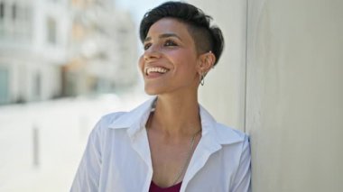 Genç, güzel İspanyol kadın yan tarafa bakıyor. Sokakta saçlarını tarıyor.