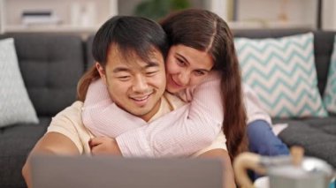 Man and woman couple using laptop hugging each other at home