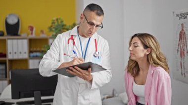 Kadın, erkek, doktor ve hasta klinikte sağlık raporu yazıyor.