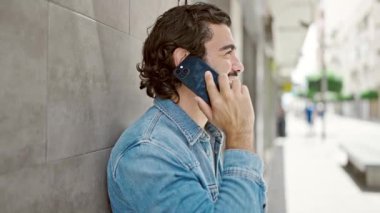 Genç İspanyol adam gülümsüyor. Kendine güveniyor. Sokakta akıllı telefondan konuşuyor.