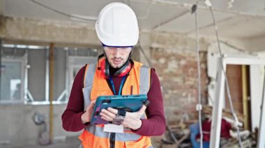 Touchpad kullanan genç İspanyol müteahhit inşaat alanına bakıyor.