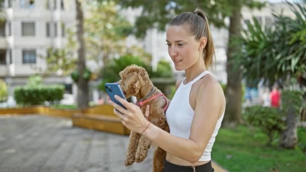 Молодая Белая Женщина Улыбающейся Собакой Обнимается Делает Селфи Смартфоном Парке — стоковое видео