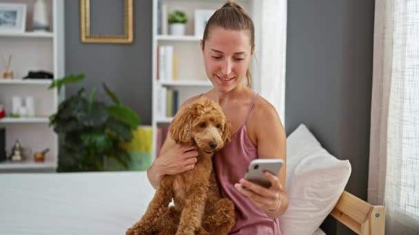年轻的高加索女人 带着狗 用智能手机坐在卧室的床上 — 图库视频影像