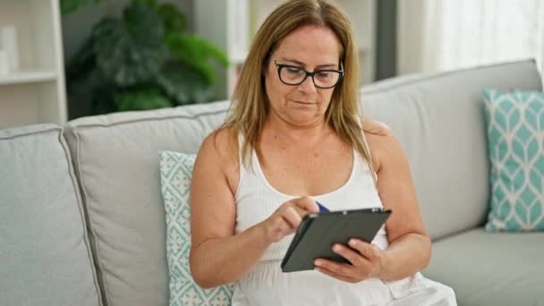 Middle Age Hispanic Woman Using Touchpad Sitting Sofa Home — Wideo stockowe
