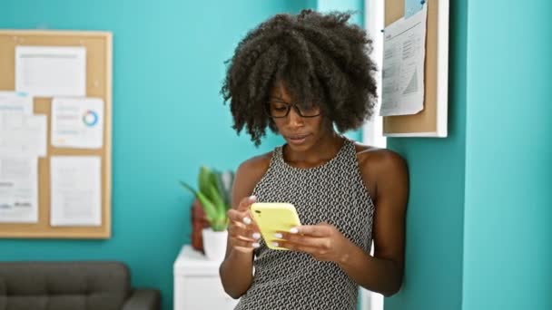 在办公室用智能手机自信地微笑着的非裔美国女商人 — 图库视频影像