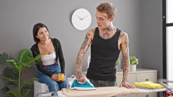 Piękna Para Uśmiechnięta Pewnie Prasowanie Ubrania Picie Kawy Pralni — Wideo stockowe