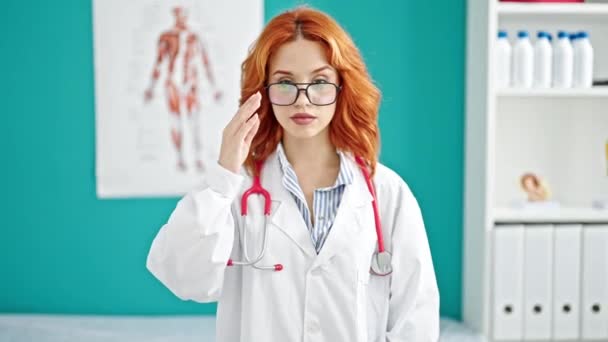 红头发的年轻女医生站在诊所里 表情严肃 — 图库视频影像
