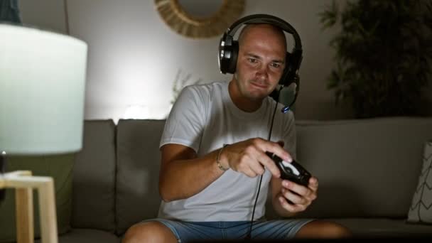 自宅で動揺しているソファーに座ってビデオゲームをしている若いヒスパニックの男 — ストック動画