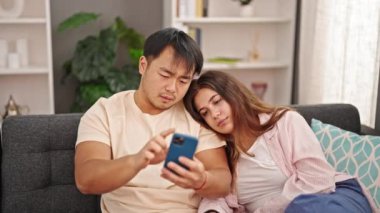 Erkek ve kadın çift evde akıllı telefon kullanıyor.