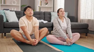 Erkek ve kadın çift evde yoga egzersizi yapıyor.