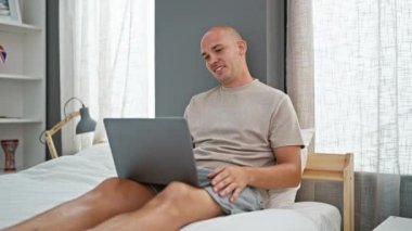 Genç İspanyol, yatak odasındaki yatakta dizüstü bilgisayarla video görüşmesi yapıyor.