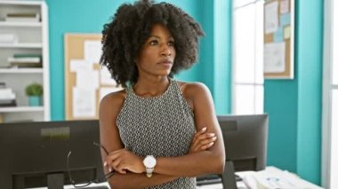 Afrika kökenli Amerikalı iş kadını kollarını kavuşturup ofiste bardakları tutuyor.