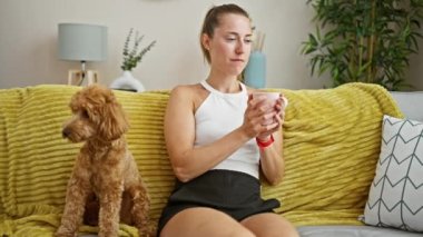 Kafkasyalı, köpekli genç bir kadın kahve kokusu alıyor evdeki kanepede oturuyor.