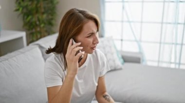 Telefonda konuşan genç bir kadın. Kanepede oturmuş, evde tartışıyor.