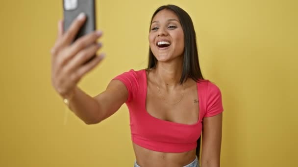 孤立した黄色の背景にビデオ通話を持つ自信を持って微笑む若いラテン語の女性 — ストック動画