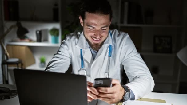 Klinikte Çalışan Genç Spanyol Doktor Dizüstü Bilgisayar Akıllı Telefon Kullanıyor — Stok video