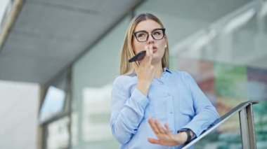 Genç sarışın iş kadını sokakta çalışan akıllı telefonuyla sesli mesaj gönderiyor.