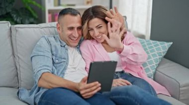 Man and woman couple having video call sitting on sofa at home