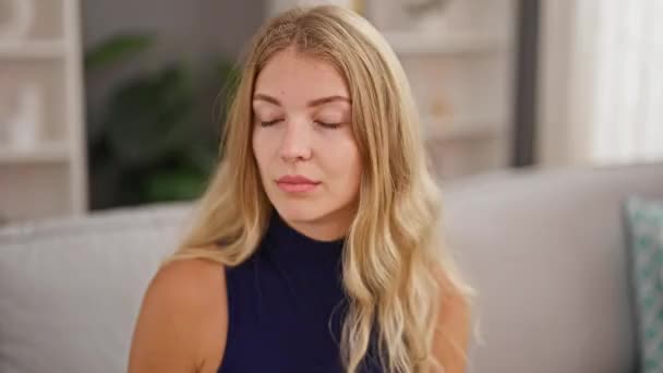 自宅で咳をしているソファーに座っている若い金髪の女性 — ストック動画