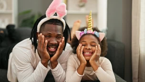 身穿滑稽睡衣的非裔美国人父亲和女儿躺在沙发上 微笑着回到家里 — 图库视频影像