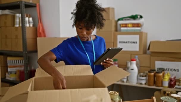 Mujer Afroamericana Voluntaria Usando Touchpad Comprobando Productos Paquete Centro Caridad — Vídeo de stock