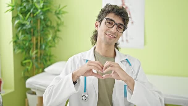 Junger Hispanischer Arzt Lächelt Bei Herzensgeste Mit Händen Klinik — Stockvideo