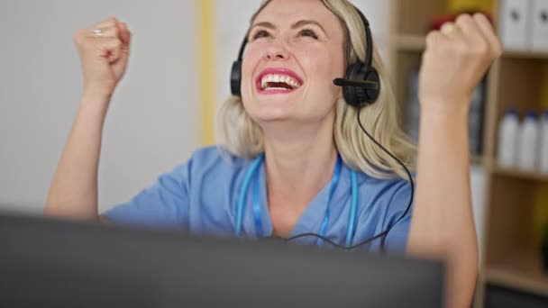 Genç Sarışın Doktor Bilgisayar Kulaklık Kullanıyor Klinikte Birinci Sınıf Jestlerle — Stok video