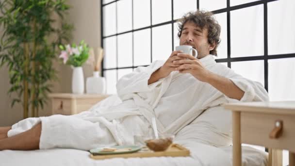 Young Hispanic Man Wearing Bathrobe Smelling Cup Coffee Bedroom — Stock Video