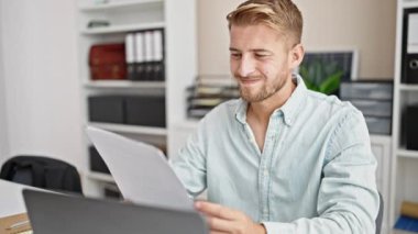 Young caucasian man business worker using laptop reading document at office