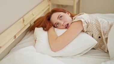 Genç kızıl saçlı kadın yatak odasında gürültü için kulaklarını kapatıyor.