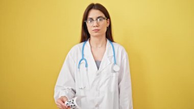 Genç, güzel İspanyol kadın doktor elinde ciddi bir ifadeyle duruyor. Sarı arka planda sana ihtiyacımız var.