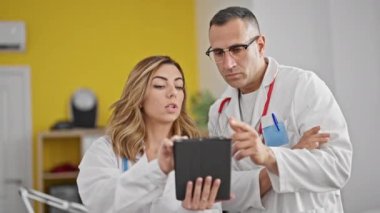Kadın ve erkek doktorlar klinikte dokunmatik bez kullanıyorlar.