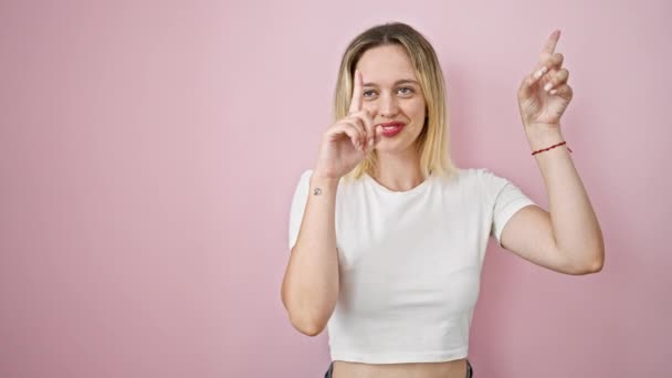 単離されたピンクの背景の上に指で側面を指で指指を指している若い金髪の女性 — ストック動画