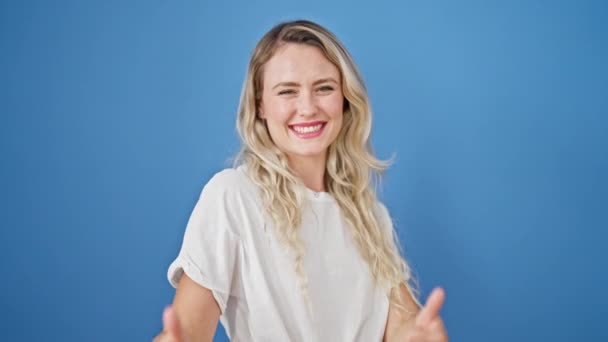 Jonge Blonde Vrouw Glimlachen Met Duimen Omhoog Geïsoleerde Blauwe Achtergrond — Stockvideo
