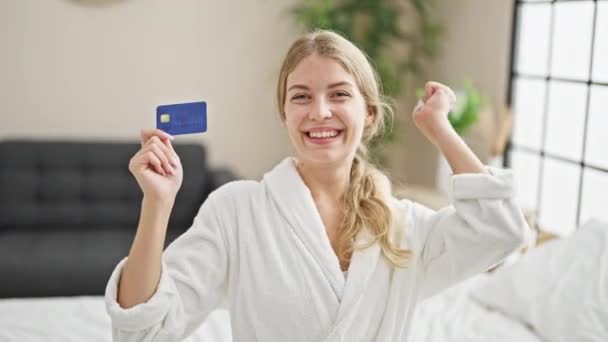 Junge Blonde Frau Bademantel Sitzt Mit Kreditkarte Bett Und Feiert — Stockvideo