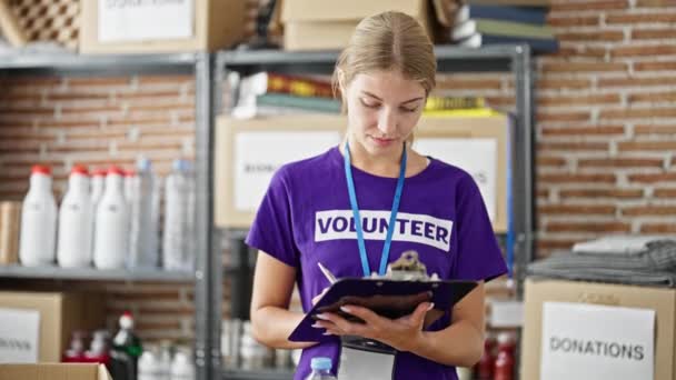 Joven Mujer Rubia Voluntaria Sonriendo Confiada Escritura Lista Verificación Centro — Vídeos de Stock