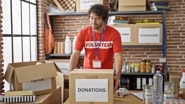 Молодий Іспаномовний Чоловік Волонтер Тримає Пожертвування Картонної Коробки Благодійному Центрі — стокове відео