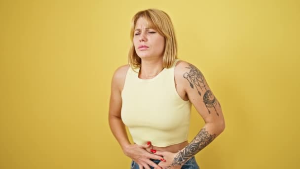 孤立した黄色の背景の上に立っている胃の痛みに苦しむ若い金髪の女性 — ストック動画